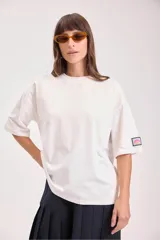 Remera de corte oversize y mangas cortas, color blanco, con cuello redondo y detalle de etiqueta pequeña en la manga.