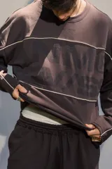 Buzo crewneck color chocolate, de tela rústica liviana, con estampado en el frente y la espalda. Presenta líneas blancas decorativas en el pecho y los brazos, y bordes deshilachados en los puños y el dobladillo.