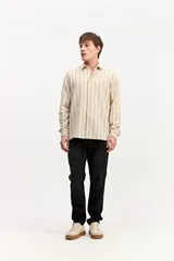 Camisa de manga larga color beige, de tejido texturado con cierre frontal de botones y cuello camisero clásico.