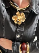 Collar con cordón trenzado de cuero sintético negro y dije redondo plateado con centro de piedra blanca con pintitas negras.