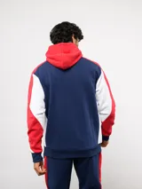 Campera deportiva Umbro del Club Nacional de Football, con cierre frontal, capucha ajustable con cordones y diseño en bloques de color azul, celeste y blanco. Presenta el logo de la marca y el escudo del club bordados en el pecho.