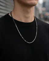 Collar compuesto por una secuencia de pequeñas piedras naturales cúbicas de color oscuro intercaladas con esferas metálicas plateadas.