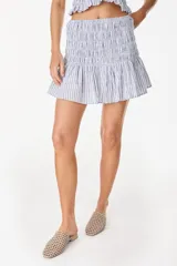 Minifalda de algodón a rayas celestes y blancas, con cintura elástica fruncida en panal de abeja y vuelo con volado ancho en el ruedo.