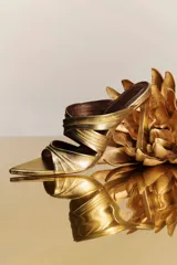 Sandalia dorada de cuero con tacón alto acampanado y punta fina.