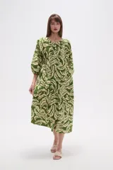 Vestido midi holgado con estampado de hojas en tonos verde y beige, cuello redondo con abertura en V y botones, y mangas 3/4 abullonadas.