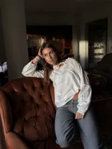 Camisa blanca de manga larga con escote a la base y detalles de blonda en cuello y mangas.