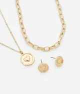Conjunto de bisutería compuesto por dos collares en capas y un par de aros tipo botón. Uno de los collares presenta una cadena de eslabones gruesos, mientras que el otro incluye una cadena fina con un dije circular con relieve de corazón. Los aros a juego presentan el mismo diseño de botón con corazón central.