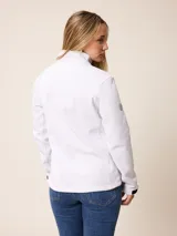 Campera softshell blanca con cierre frontal completo, cuello alto y bolsillos laterales. Presenta un bolsillo vertical con cierre en el pecho y el logo de la marca bordado.