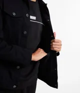 Campera de sarga negra, modelo trucker, con cuello camisero, recortes, dos bolsillos delanteros con solapa y abotonado total.