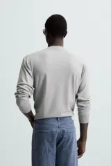 Jersey color crudo de tejido de punto, con cuello redondo y mangas largas. Corte amplio y terminaciones en rib.