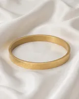 Esclava rígida de acero con baño de oro, con diseño de flores grabadas en toda su superficie.