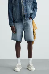 Bermuda de denim de algodón, color verde claro lavado, de corte recto y tiro medio. Presenta cinco bolsillos y cierre frontal con cremallera y botón.
