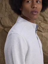 Fleece de algodón color gris melange, con cuello alto y cierre frontal parcial. Diseño de manga larga con puños y ruedo acanalados.