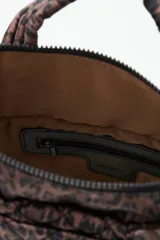 Bolso tipo tote mini acolchado con estampado de leopardo en tonos marrones y negros. Presenta asas cortas acolchadas y una correa larga ajustable con inscripción. Incluye un llavero colgante con letras negras.