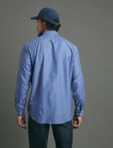 Camisa de vestir de corte clásico, color azul, con cuello italiano, cierre frontal de botones y bolsillo en el pecho.