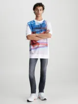 Pantalón de jean gris oscuro de corte slim, con cintura media, cinco bolsillos y cierre con cremallera.