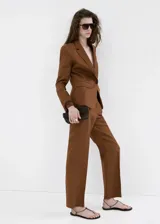 Pantalón marrón de lino, corte recto de tiro medio, con bolsillos laterales y traseros de ribete, trabillas y cierre oculto.