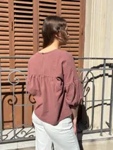 Blusa color chocolate de diseño holgado, con cuello redondo, frunce frontal y mangas abullonadas con puños ajustados.