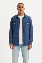 Camisa de jean estilo western con canesú característico, cuello camisero, manga larga y cierre frontal con botones a presión perlados. Cuenta con dos bolsillos frontales con solapa y etiqueta roja distintiva de la marca.
