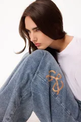 Jean de corte holgado en denim azul claro, con bordado del logo de la marca en color ocre en el lateral de la pierna.