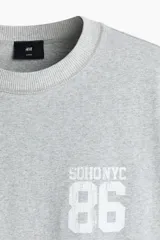 Remera gris melange de punto pesado de algodón, de corte holgado con hombros caídos, cuello redondo acanalado y bajo recto. Cuenta con un diseño estampado en el pecho con las inscripciones 'SOHONYC' y '86'.