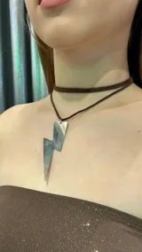 Gargantilla marrón con dije plateado en forma de rayo.