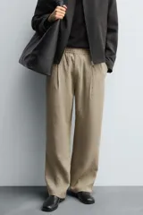 Pantalón negro de corte relajado con cintura elástica ajustable y pliegues en la parte delantera. Presenta bolsillos laterales y bolsillos traseros de parche.