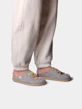 Pantuflas de fieltro color gris, abiertas en el talón, con delicados bordados florales multicolores en el empeine y detalle de trenza de yute en la suela.