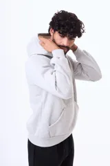 Buzo con capucha y bolsillo frontal tipo canguro, confeccionado en tela de felpa, con cordones ajustables en el cuello y puños elásticos.