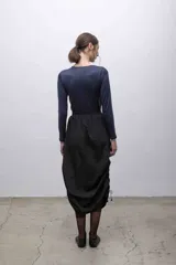 Top negro de mangas largas con frunces en el hombro izquierdo.