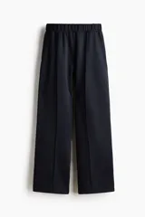 Pantalón de corte holgado en punto pesado con leve brillo, color negro. Modelo con elástico revestido en la cintura, bolsillos al bies y piernas rectas con pliegues cosidos.
