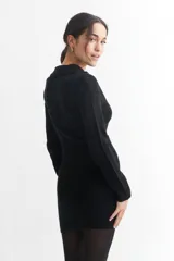 Vestido corto de tejido de punto acanalado en color negro, con cuello polo y cierre frontal parcial. Presenta mangas largas y un ajuste entallado al cuerpo.