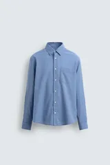 Camisa de hombre de manga larga, color azul, con cuello solapa y bolsillo plastrón en el pecho. Presenta un patrón de cuadros pequeños en tonos de azul y blanco.