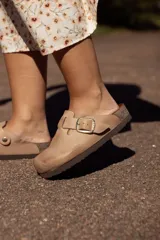 Zueco color tostado con hebilla dorada ajustable, plantilla anatómica y suela de goma.