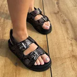 Sandalias negras con estampado animal print, confeccionadas en cuero vacuno, con doble tira ajustable con hebillas metálicas y suela de goma micro forrada en cuero.