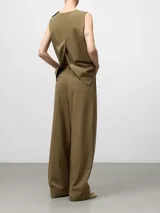 Pantalón de vestir ancho color caqui, con pinzas delanteras, trabillas en la cintura y bolsillos laterales y de vivo traseros.
