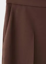Pantalón de vestir marrón de tiro alto y diseño recto, con bolsillos laterales y cierre oculto con botón, gancho y cremallera.