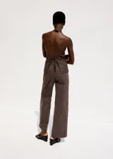 Pantalón de jean marrón con costuras frontales marcadas y corte recto.
