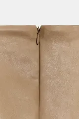 Vestido mini de efecto piel color tostado, con cuello barco, diseño sin mangas (manga sisa) y cierre en la espalda con cremallera oculta.