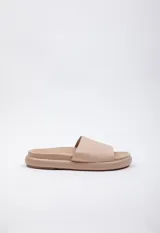 Sandalia baja color beige de símil cuero, con cinta ancha sobre la capellada y plataforma de 2 cm de alto.