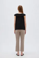 Blusa negra de viscosa sin mangas, con cuello redondo, volados frontales y detalle de lazo en el escote.