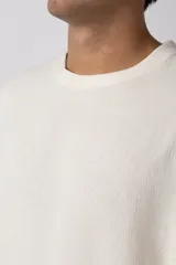 Remera de manga corta con cuello redondo, confeccionada en tejido de lino con textura entramada y corte holgado.