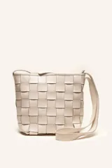 Cartera tipo morral de cuero color beige, con diseño trenzado artesanal, correa larga regulable y cierre superior.