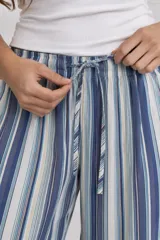 Pantalón largo de corte ancho, con diseño de rayas verticales en tonos azules, celestes y blancos, cintura elástica con cordón ajustable y bolsillos laterales.