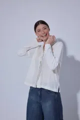 Blusa de diseño romántico con frente de lino y espalda y mangas de algodón con spandex. Presenta un cierre frontal con botones y un delicado detalle de mini volado en la pechera.