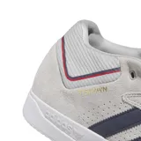 Championes de skate Adidas modelo Tyshawn, color gris claro con las icónicas tres rayas laterales en azul oscuro. Presenta detalles en rojo y azul en el talón, suela blanca y el nombre del modelo grabado en dorado en el lateral.