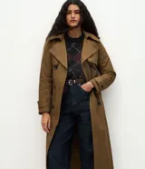 Trench coat largo de Marfinno, confeccionado en gabardina de poliéster. Presenta cuello con solapas, aletas en los hombros, cierre frontal con botones y cinta para lazo en la cintura.