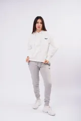 Canguro de frizza color blanco, con capucha, cordones ajustables y bolsillo frontal tipo canguro. Presenta un pequeño logo bordado en el pecho.