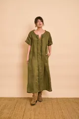 Vestido tipo túnica de lino color verde militar, de manga corta, con escote en V y volados frontales. Cuenta con bolsillos laterales y diseño holgado.