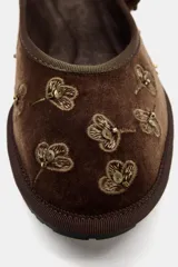 Bailarina plana de terciopelo marrón con bordados florales y detalles de lentejuelas. Cuenta con escote redondo y una tira con hebilla metálica en el empeine.